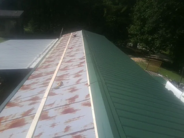 Old rusted panels beside newly installed green metal roofing — Wind Damage Roof Repair by Roofing Brothers in Dalton